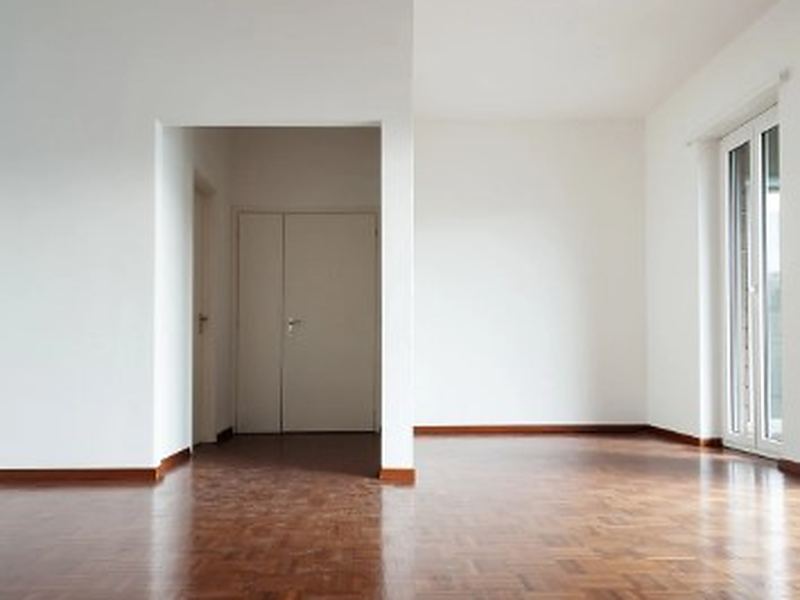 Salón de un piso heredado ya despejado, con parquet y puertas blancas