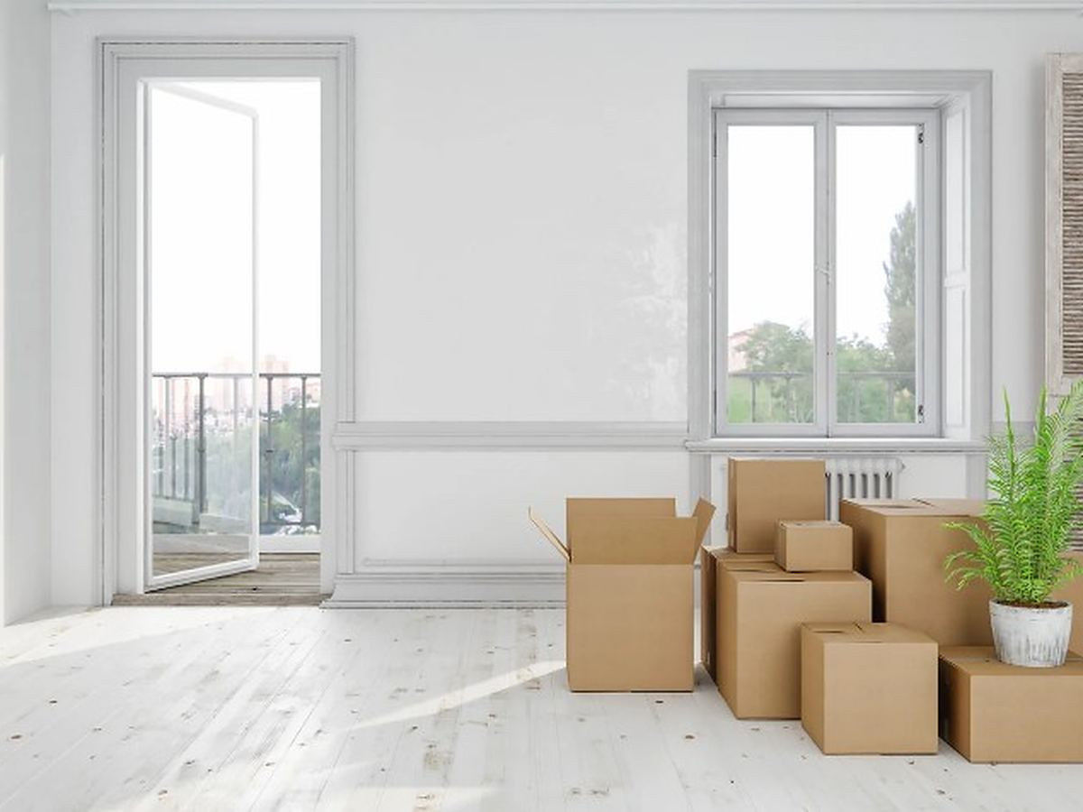 Salón con cajas de mudanza apiladas junto al balcón, preparado para el traslado