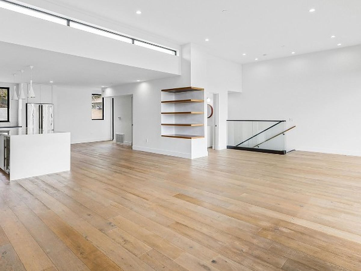 Planta diáfana de un chalet ya vaciado, con cocina abierta y escalera al fondo