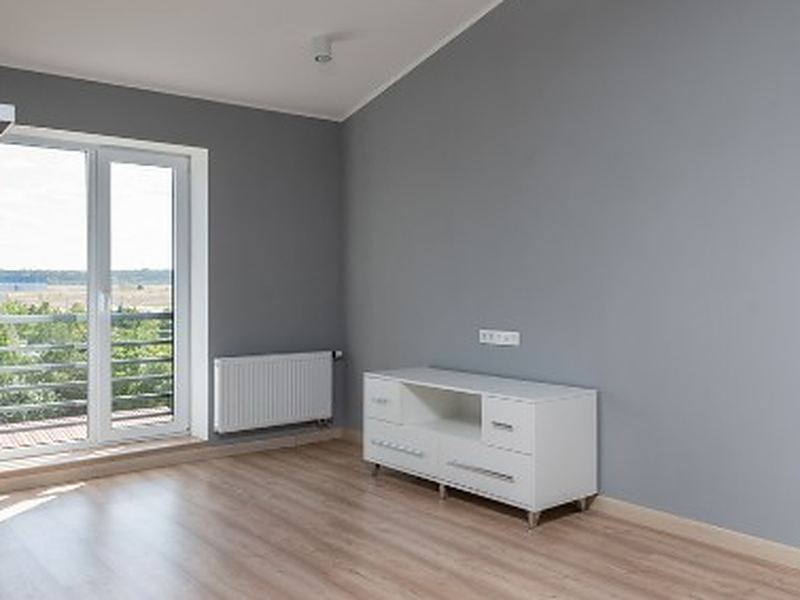 Dormitorio vacío con suelo laminado y ventana al exterior tras el vaciado